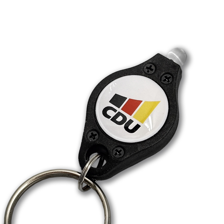 Kleine LED-Leuchte am Schlüsselring. Gehäuse schwarzer Kunststoff. Aufdruck: weißer Kreis mit 3-farbigem CDU-Logo.