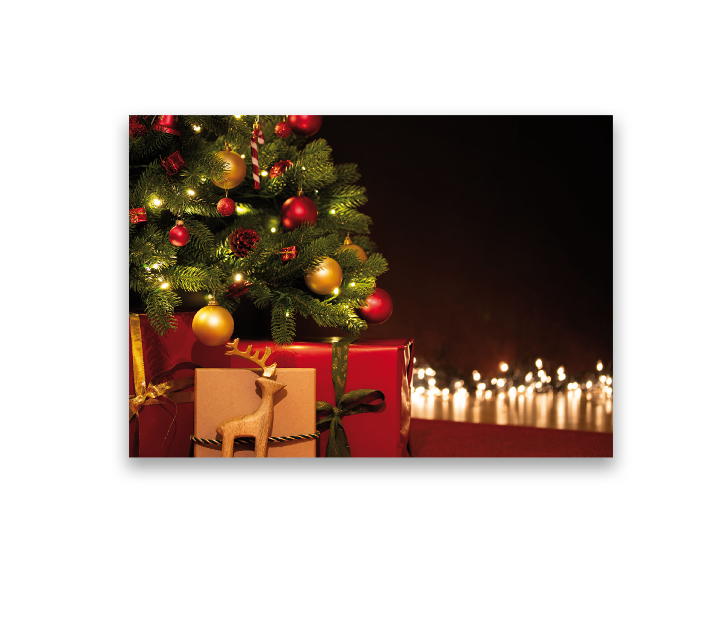 Weihnachtskarte-Vorderseite. Tannenbaum mit vielen Lichtern und Geschenken vor dem Baum.