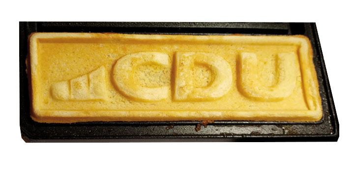 Abbildung einer gebackenen Waffel mit geprägtem CDU-Logo. Waffel hat eine länglich, quadratische Form.