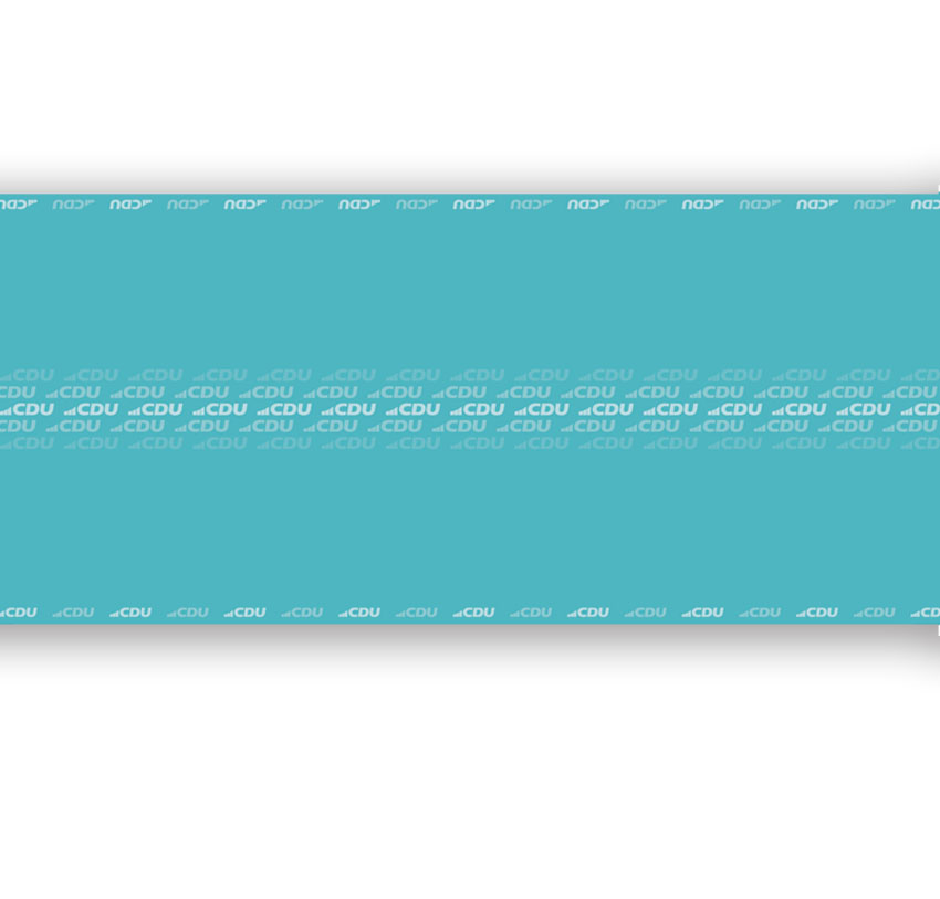 Plan ausgerollte Papiertischdecke. Ganz in Türkis mit kleinen weißen und helltürkisen CDU-Logos an den Längsseiten der Papierrolle und mittig in mehreren Reihen untereinander aufgedruckt.